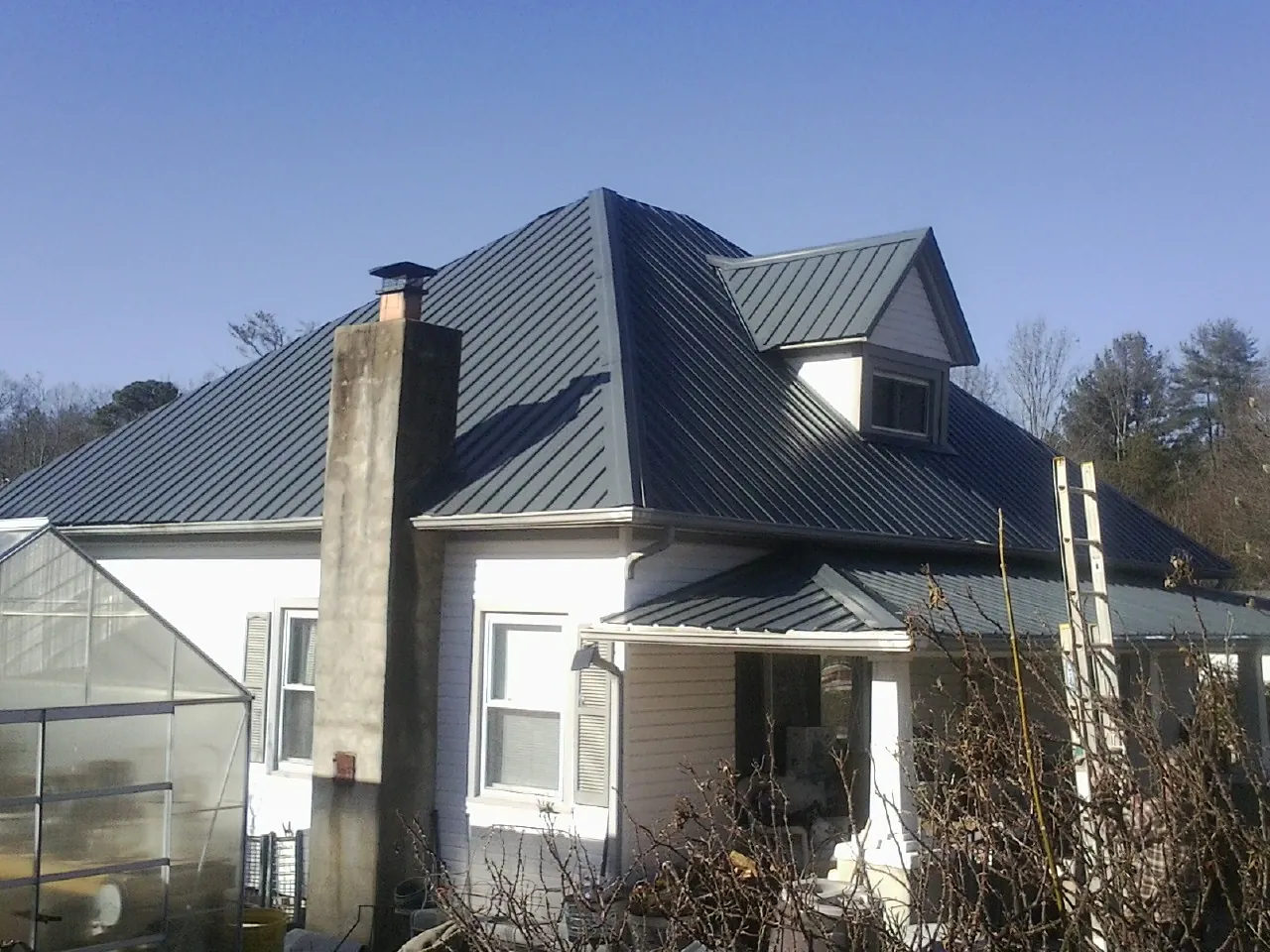 Dark blue standing seam metal roof on a white farmhouse with dormer — Slate & Tile Roof Repair by Roofing Brothers in Atmore