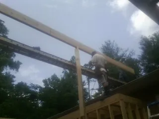 Carpenter setting a ridge beam over a new addition frame — Ice Dam Removal by Roofing Brothers in Atmore