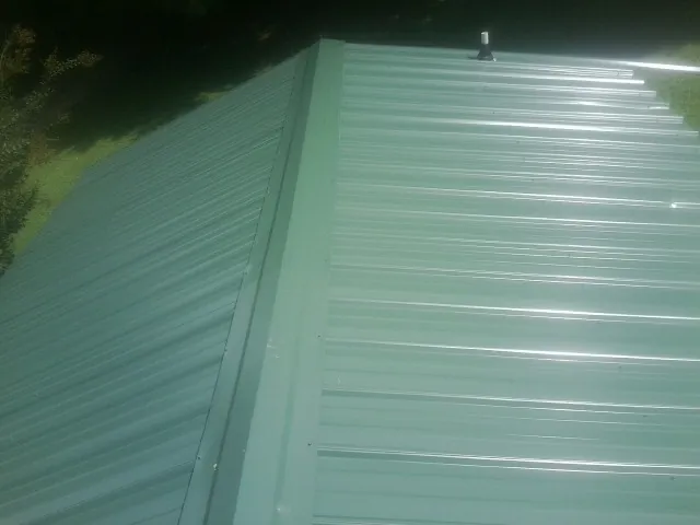 New green metal panels meeting at the ridge of a roof — Flat Roof Repair work by our crew in Atmore