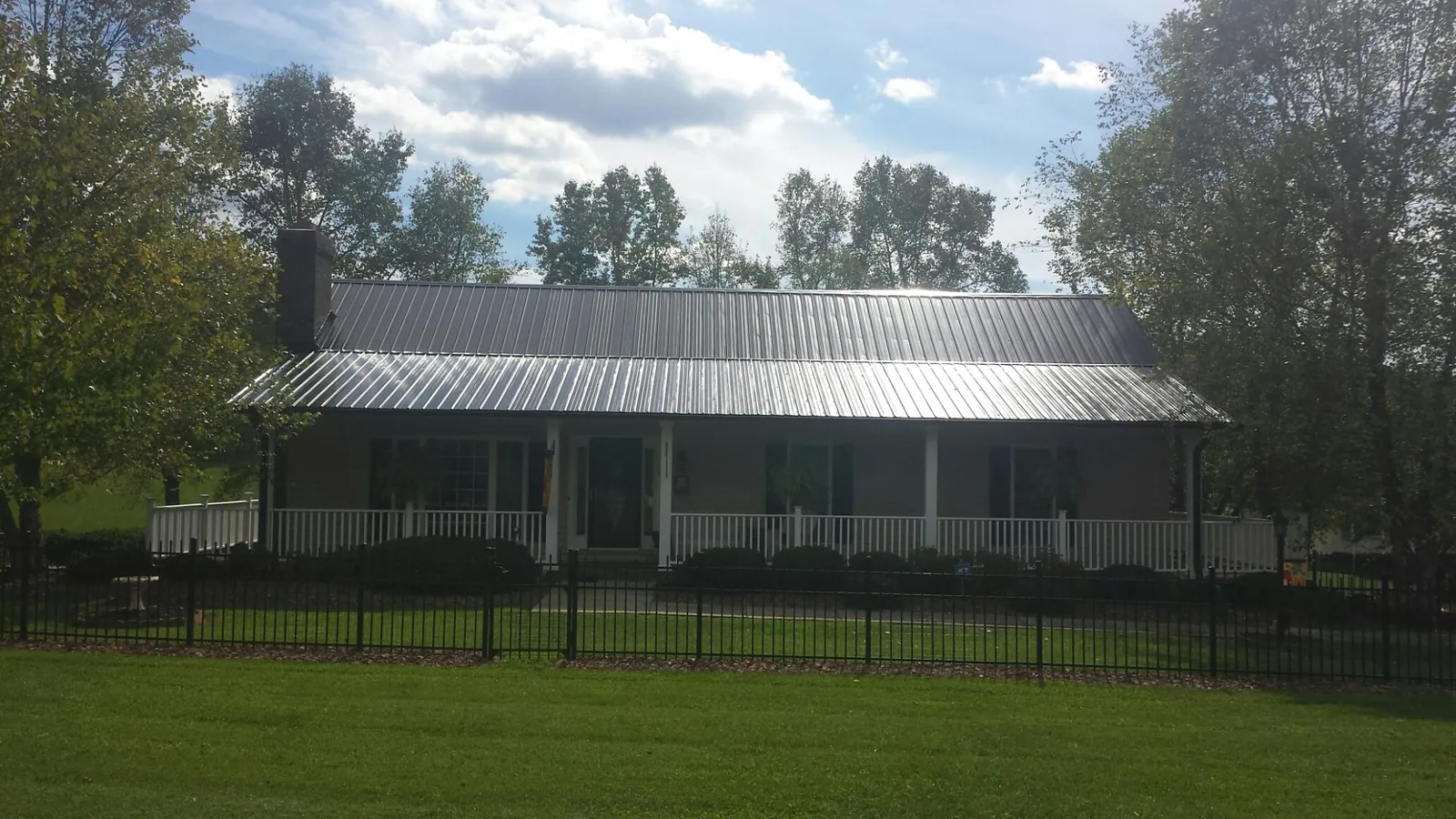 Gray metal roof on a brick ranch with a full width front porch — Gutter Guard Installation work by our crew in Atmore