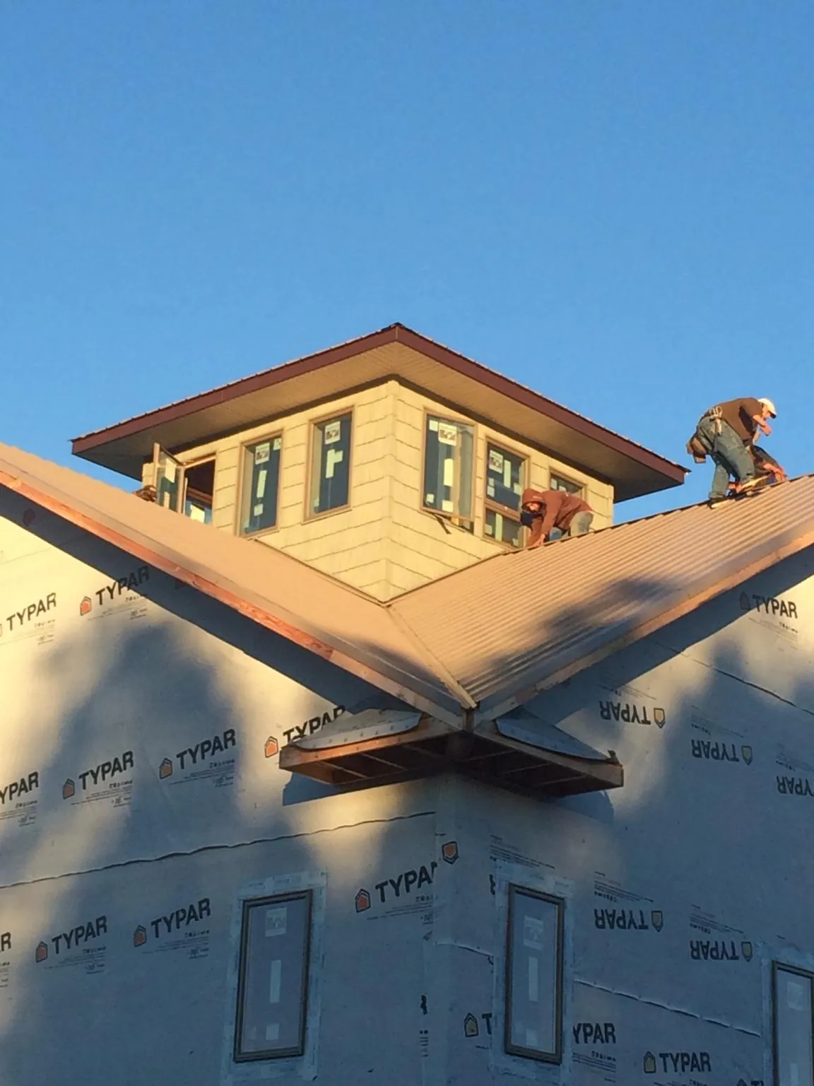Roofers working around a rooftop cupola on a new metal roof at sunset — Roof Waterproofing in Atmore by Roofing Brothers